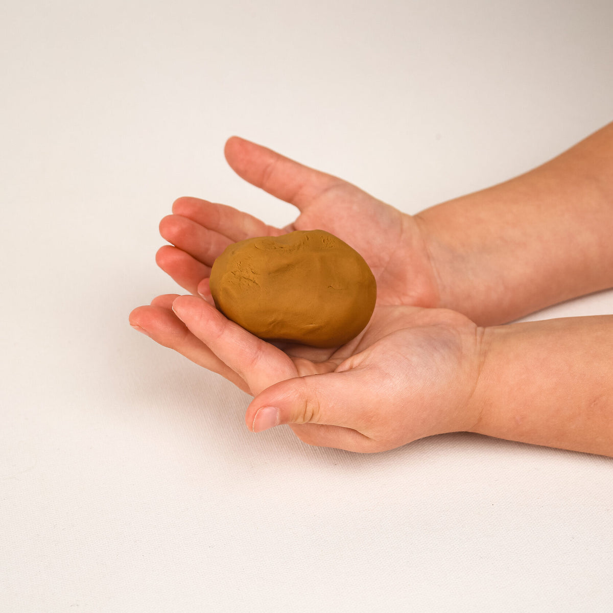 Sustainable ochre-hued play dough – non-toxic, earth-toned clay designed for children to mold realistic figures representing dark-skinned individuals
